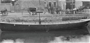 Pilchard seine boat on the River Kenwyn at Back Quay in Truro, with Samuel Brokenshire carriage factory in the background. A number of carts and carriages are parked on the quay, with a number of onlookers who are possibly workers from the factory. The coach builder, Samuel Brokenshire (also a shoeing smith) is recorded in Kelly's Directory, 1889, at Back Quay, Royal Hotel Yard, Truro. The main Fisheries Exhibition site was a field at the top of Lemon Street and the exhibition ran from 25th July 1893 for a month. Number 11 in a series of glass lantern slides recording the Fisheries Exhibition. 