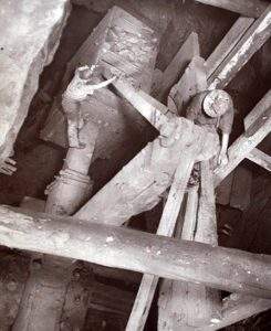 Miners here stand on narrow beams as they arrange machinery